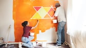 Menschen streichen eine Wand orange