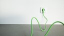 Grünes Kabel steckt in Steckdose