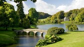Gartenkunst: Blick auf Fluss mit steinerner Brücke in einem englischen Landschaftsgarten