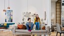 Junges Paar, das auf seiner Couch in einem modern eingerichteten Zuhause sitzt