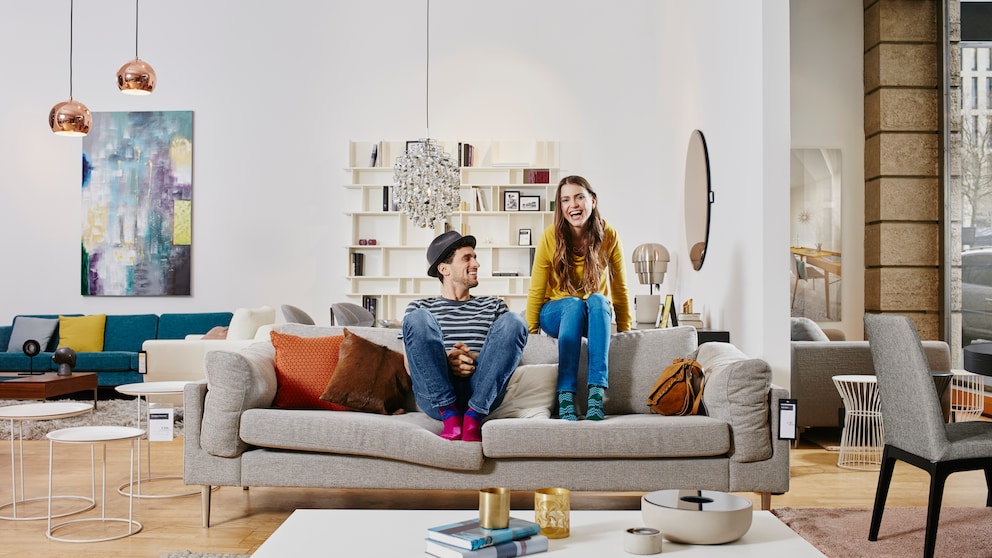 Junges Paar, das auf seiner Couch in einem modern eingerichteten Zuhause sitzt