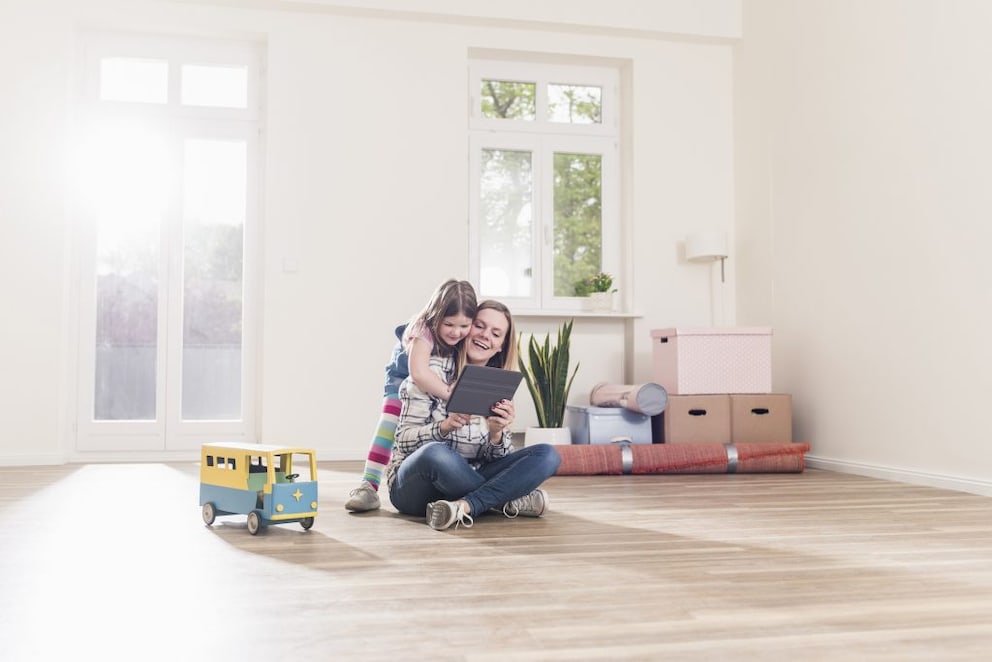 Mother sitting on the floor being hugged by her child. Together they plan the design of the child's room.