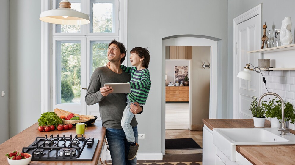 Vater und Sohn stehen an einem Tisch und schauen zur Lampe