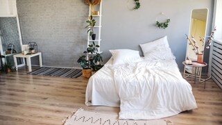 Originell eingerichtetes Schlafzimmer mit asymmetrischer Anordnung von Dekoleiter, Pflanzen, Spiegel und Beistelltisch