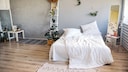Originell eingerichtetes Schlafzimmer mit asymmetrischer Anordnung von Dekoleiter, Pflanzen, Spiegel und Beistelltisch