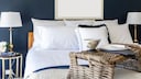 Schlafzimmer mit blauer Wand, heller Bettwäsche und Naturelementen als Accessoires