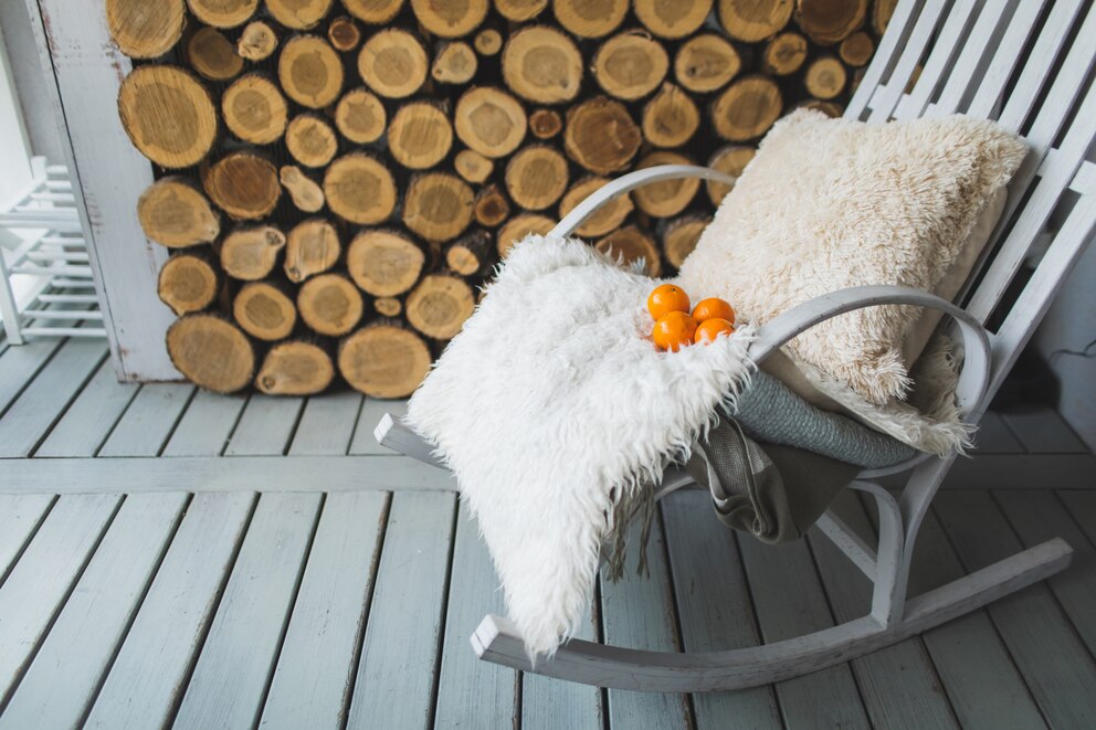 Ein Schaukelstuhl auf einem Balkon mit Lammfell und Winterdeko