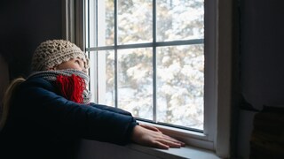 Kind schaut im Winter aus Fenster