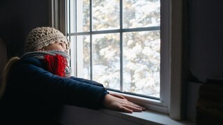 Kind schaut im Winter aus Fenster
