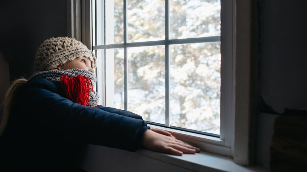 Kind schaut im Winter aus Fenster