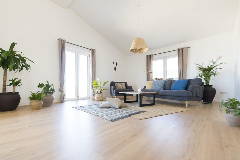 A living room with laminate flooring and rugs laid out in a layering technique