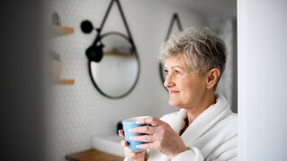 Frau mit einer Tasse Kaffee in der Hand im Badezimmer