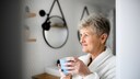 Frau mit einer Tasse Kaffee in der Hand im Badezimmer