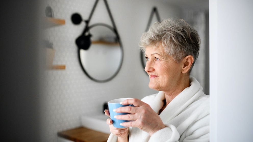 Frau mit einer Tasse Kaffee in der Hand im Badezimmer