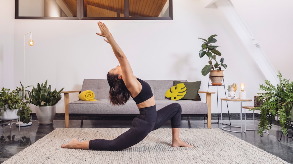 Eine Frau, die Yoga auf einem Teppich im Wohnzimmer macht