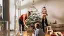 Familie stellt Weihnachtsbaum auf