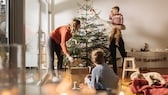 Familie stellt Weihnachtsbaum auf