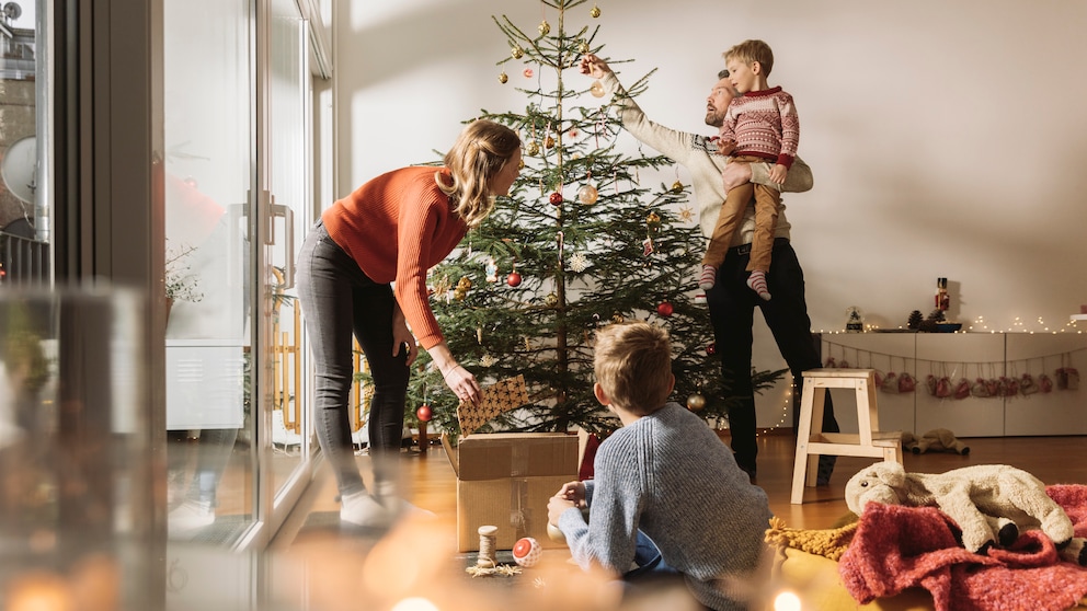 Familie stellt Weihnachtsbaum auf