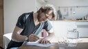 Grundsteuererlass: Ein Mann f&uuml;llt Formulare aus