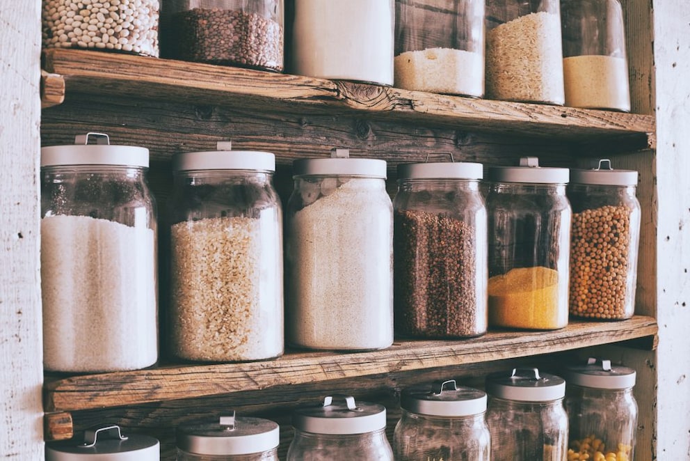 Dry food supplies in glass containers on solid wood shelves