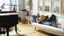 Mann liegt auf Couch in Wohnung