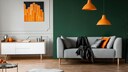 Raum mit drei Farben einrichten: Ein Wohnbereich mit dunkelgr&uuml;ner Wand, hellgrauem Sofa und Orange als Akzentfarbe