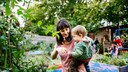 Urbane G&auml;rten: Eine Frau h&auml;lt ein Kind auf dem Arm in einem Garten