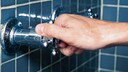 Hand dreht an Duschknauf