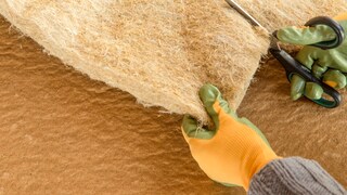 Person, die Dämmwolle aus Hanffasern zuschneidet