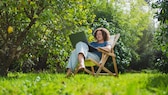 Frau sitzt mit Laptop im Garten