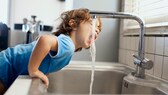 Junge trinkt aus einem Wasserhahn