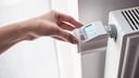 Eine Frau stellt die Temperatur an einem digitalen Thermostat ein
