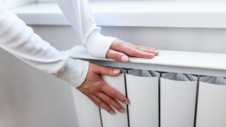 Frau hält Hände an Heizung