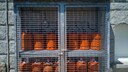 Gasflaschen: Viele rote Gasflaschen hinter einem Gitter gesichert