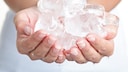 Frau hält Eiswürfel in der Hand