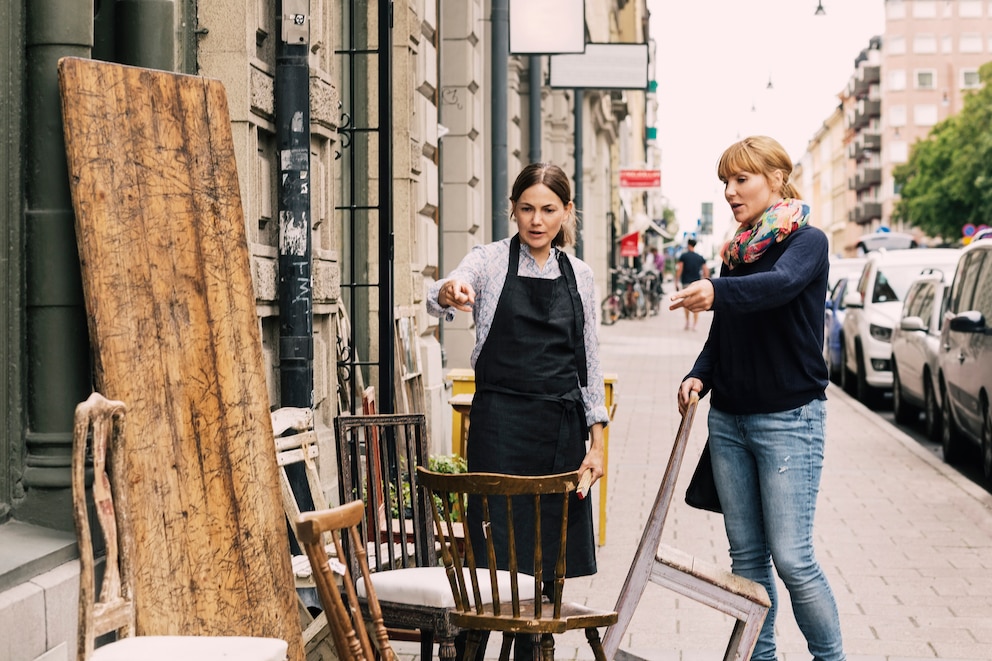 Zwei Frauen, die vor einem Laden mit alten Möbeln stehen