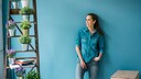 Frau, die vor einer blau gestrichenen Wand steht