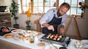 Mann bereitet Gemüse und Fleisch auf einem Elektrogrill bzw. Tischgrill vor.