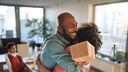 Vater umarmt Kind mit Geschenk in der Hand.