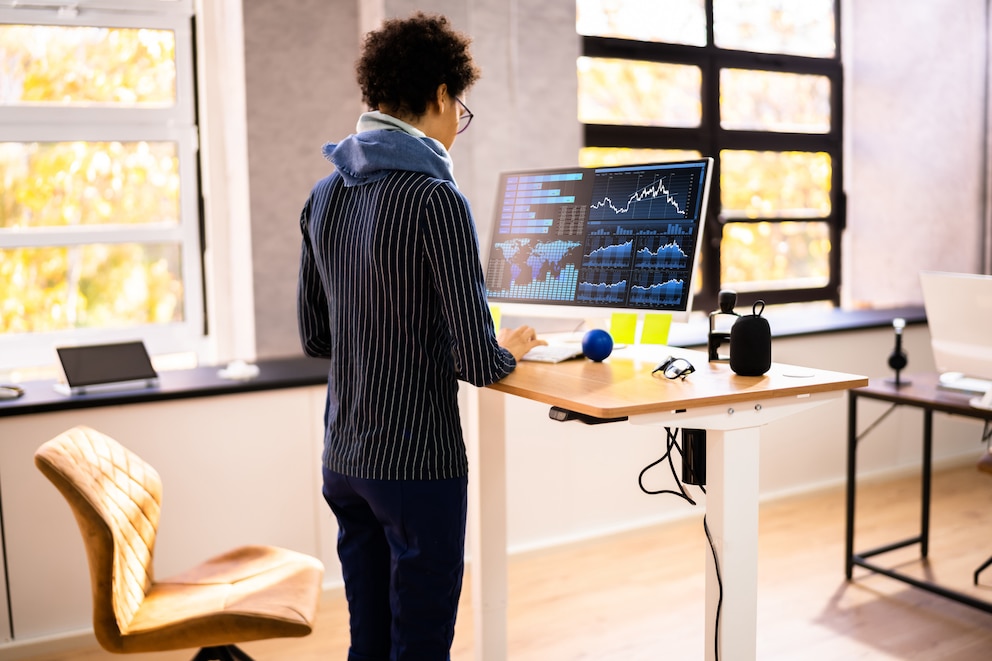 Person, die an einem Steh-Sitz-Tisch arbeitet