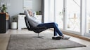 Mann sitzt im Lounger auf flauschigem Teppich