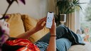 Frau mit Handy liegt auf dem Sofa