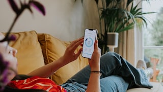 Frau mit Handy liegt auf dem Sofa