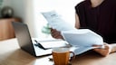 Hausgeld: Frau mit Abrechnung vor dem Laptop