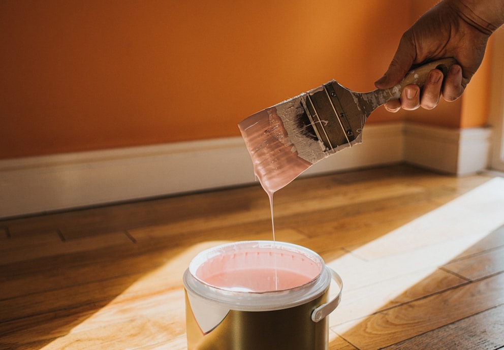 Dispersion paint drips from the brush into the paint can