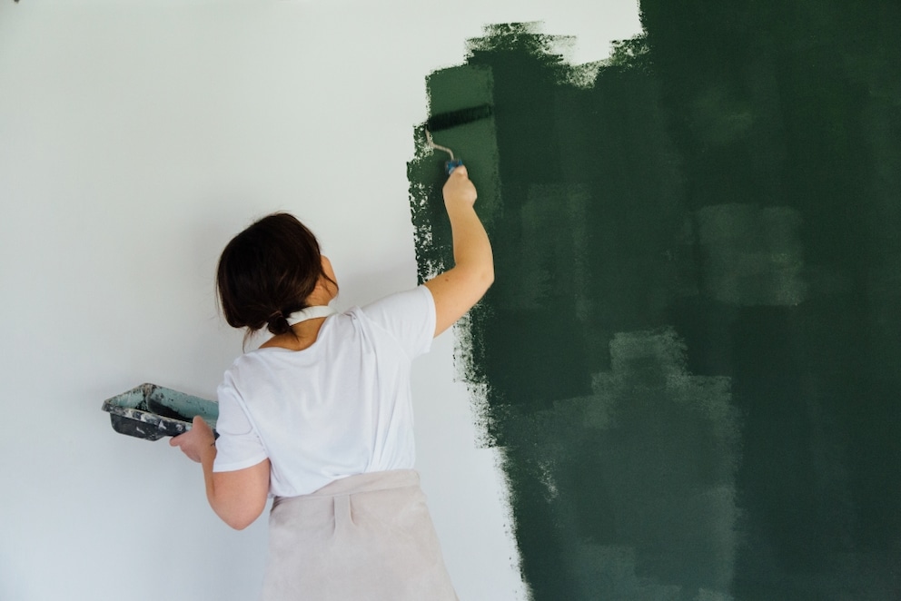 Woman painting a wall in dark green