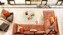 Wohnzimmer mit braunem Ledersofa und orangenen Kissen