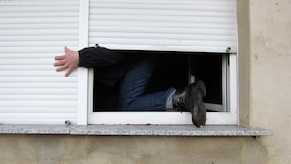 Einbrecher klettert durch Fenster