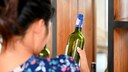 Frau schaut sich Weinflasche an und überlegt wohl, was sie mit den Weinresten drin machen kann