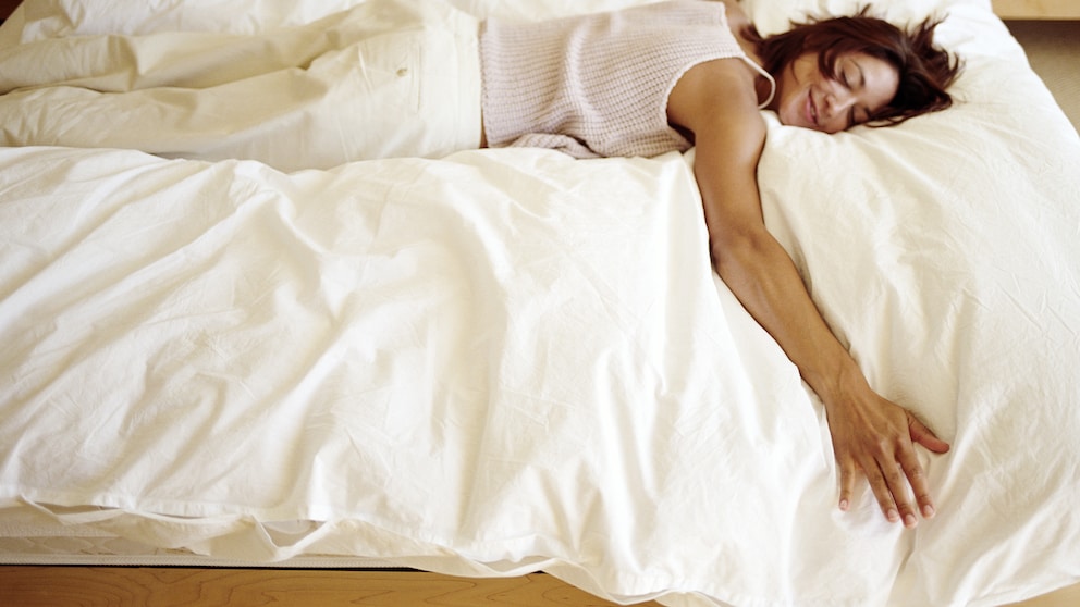 Frau liegt entspannt auf ihrem Bett